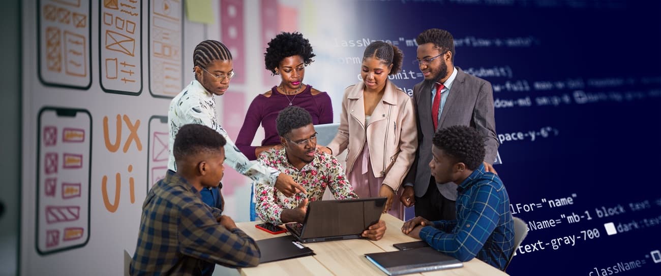 Six colleagues gathered around a laptop between a wireframe wall and a wall of code