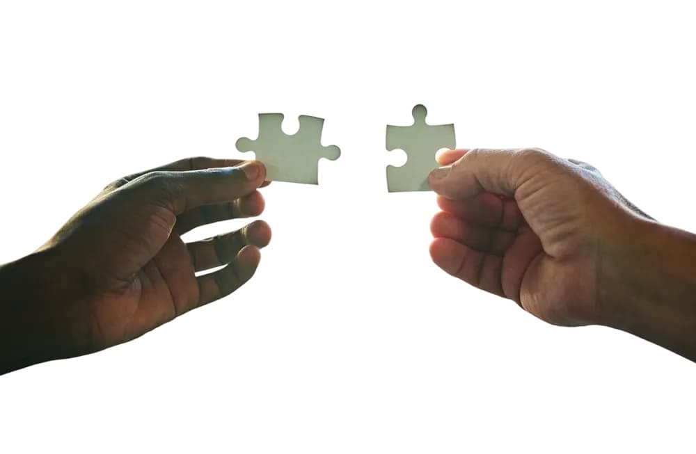 Two hands fitting puzzle pieces together